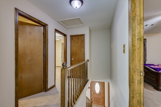 hall with a textured ceiling and light carpet