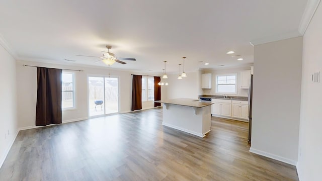 kitchen with white cabinets, a center island, ornamental molding, and decorative light fixtures