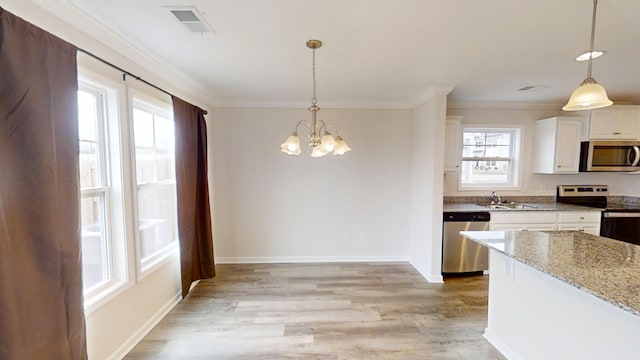 kitchen featuring stainless steel appliances, white cabinets, light stone countertops, pendant lighting, and a notable chandelier