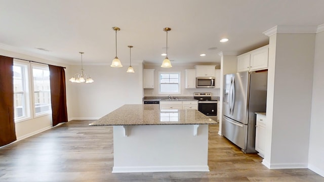 kitchen featuring a breakfast bar area, appliances with stainless steel finishes, a center island, pendant lighting, and white cabinets