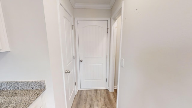 hallway with light hardwood / wood-style floors and crown molding