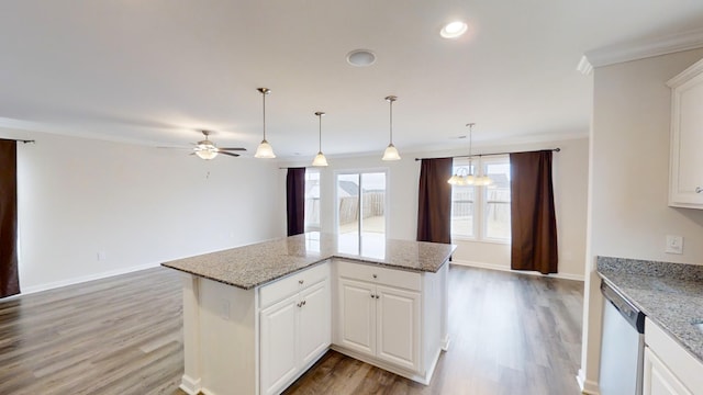 kitchen featuring stainless steel dishwasher, a kitchen island, white cabinetry, and light stone counters