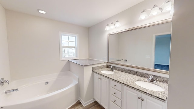 bathroom featuring vanity, a washtub, and hardwood / wood-style flooring