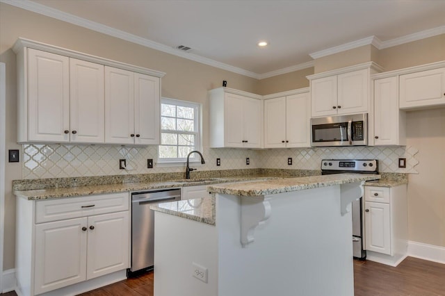 kitchen with white cabinets, dark wood-style floors, light stone counters, appliances with stainless steel finishes, and a sink