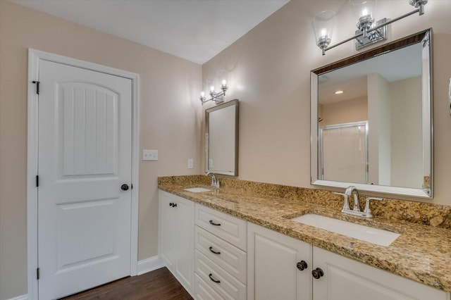 bathroom with wood finished floors, a sink, a shower stall, and double vanity