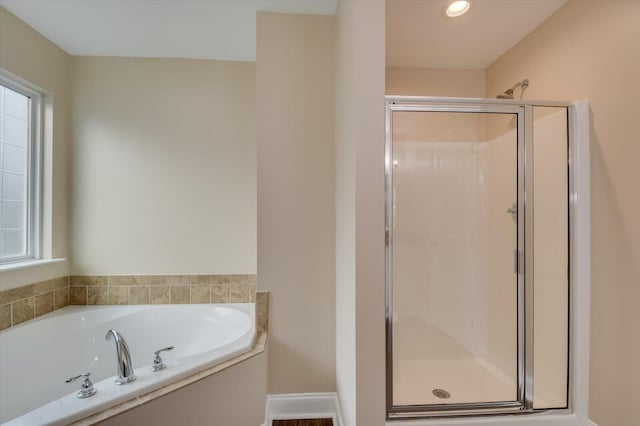 bathroom with a stall shower, plenty of natural light, baseboards, and a garden tub