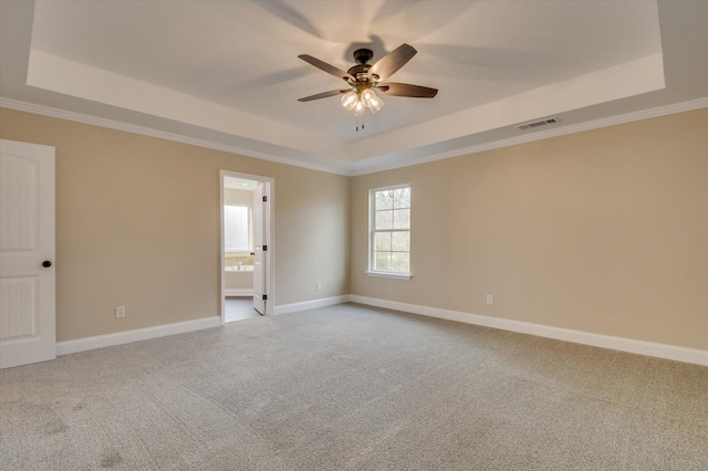 carpeted spare room with baseboards, visible vents, a tray ceiling, and ceiling fan