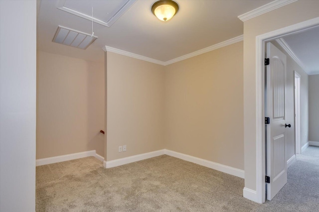 empty room with attic access, crown molding, baseboards, and carpet flooring