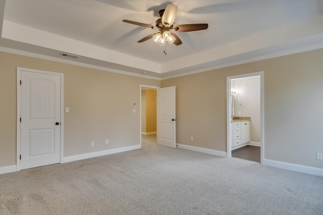 unfurnished bedroom with carpet floors, a tray ceiling, visible vents, and baseboards