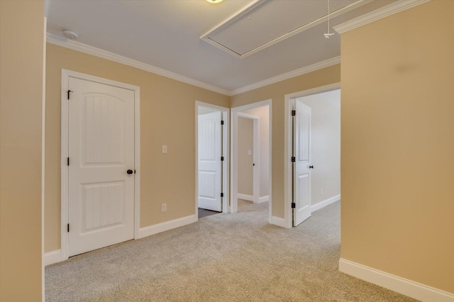 empty room featuring attic access, carpet flooring, ornamental molding, and baseboards