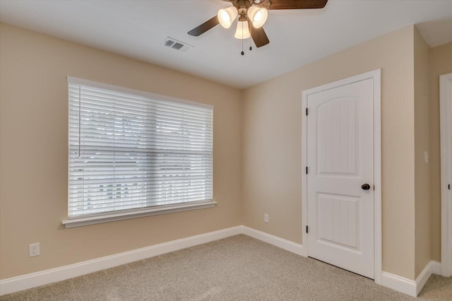 carpeted spare room with baseboards, visible vents, and ceiling fan