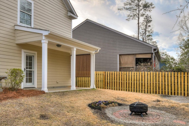 view of home's exterior with fence and a fire pit