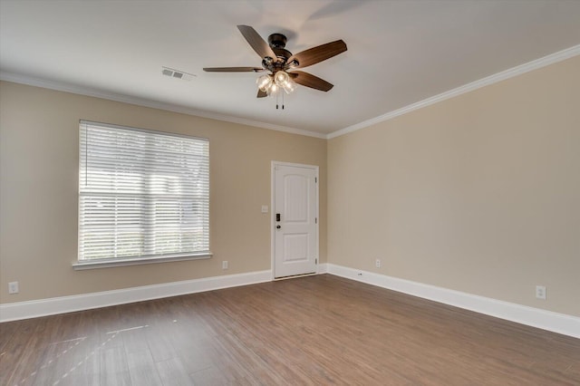 spare room with dark wood-style flooring, a ceiling fan, visible vents, baseboards, and ornamental molding