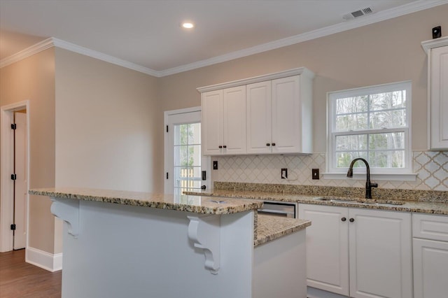 kitchen featuring crown molding, white cabinets, visible vents, and a sink