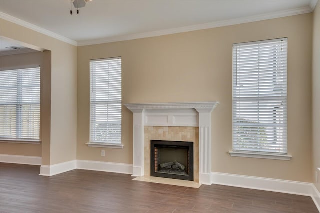 unfurnished living room with baseboards, a fireplace, ornamental molding, and wood finished floors