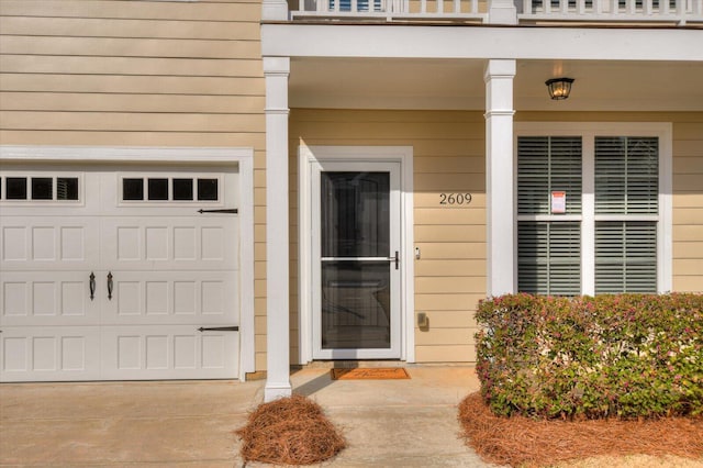 view of exterior entry featuring a garage and a balcony