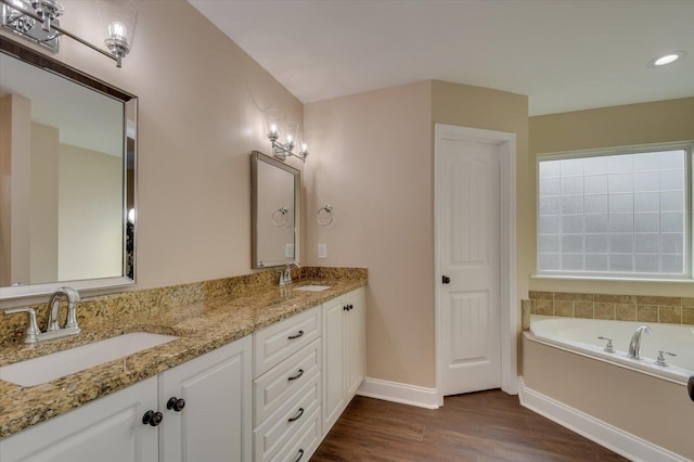 full bath with double vanity, wood finished floors, a sink, and baseboards