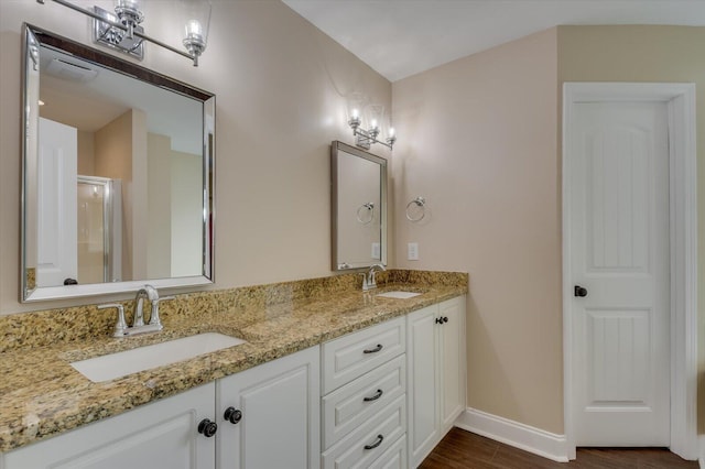 bathroom featuring double vanity, wood finished floors, a sink, and baseboards