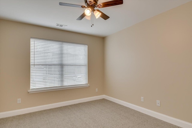 spare room with carpet flooring, visible vents, ceiling fan, and baseboards