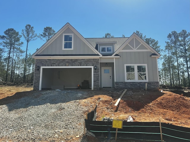 craftsman house with a garage, stone siding, board and batten siding, and gravel driveway