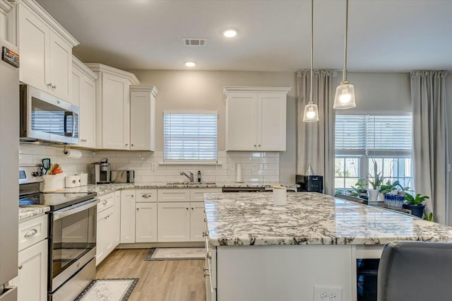 kitchen featuring white cabinetry, hanging light fixtures, a center island, and stainless steel appliances