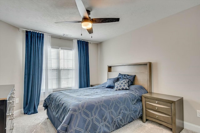 bedroom featuring ceiling fan, light carpet, and a textured ceiling