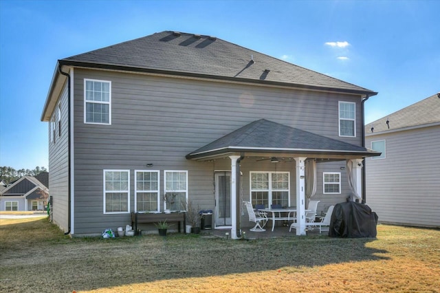 back of house featuring a lawn, ceiling fan, and a patio