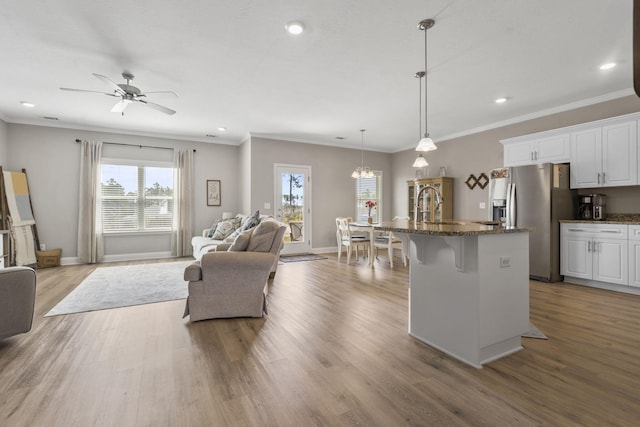 kitchen featuring a breakfast bar area, white cabinets, stainless steel fridge with ice dispenser, and dark stone countertops