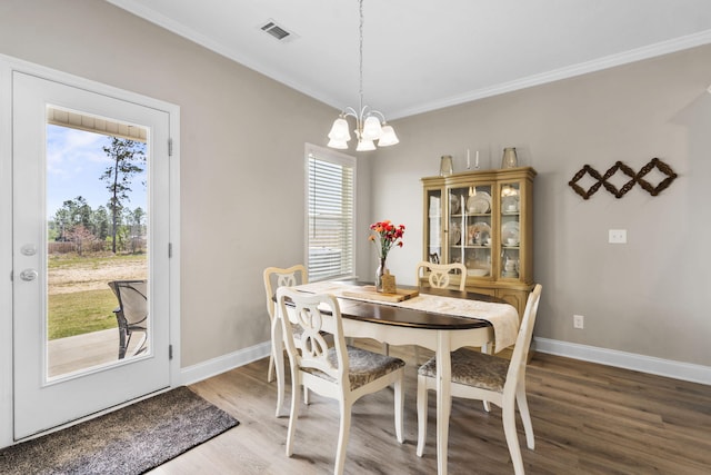dining space with visible vents, ornamental molding, wood finished floors, and a chandelier