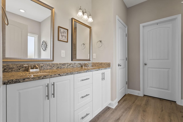 full bathroom featuring a sink, baseboards, double vanity, and wood finished floors