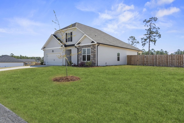 view of front of house featuring fence, a front yard, stone siding, roof with shingles, and driveway