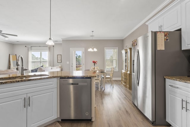 kitchen with appliances with stainless steel finishes, a sink, white cabinets, stone countertops, and light wood-style floors