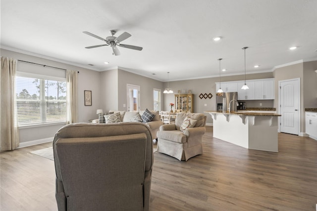 living room featuring crown molding, recessed lighting, wood finished floors, and ceiling fan with notable chandelier
