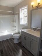 full bathroom featuring hardwood / wood-style floors, vanity, toilet, and bathtub / shower combination