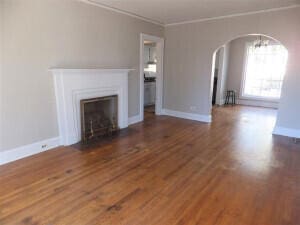 unfurnished living room featuring ornamental molding, dark wood-type flooring, and a chandelier