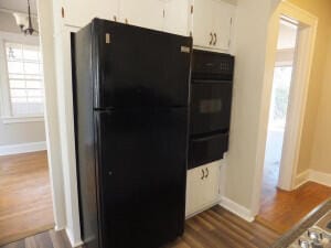 kitchen with black appliances, dark hardwood / wood-style floors, and white cabinets