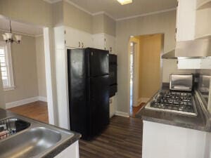 kitchen featuring white cabinetry, dark hardwood / wood-style flooring, a notable chandelier, crown molding, and black refrigerator