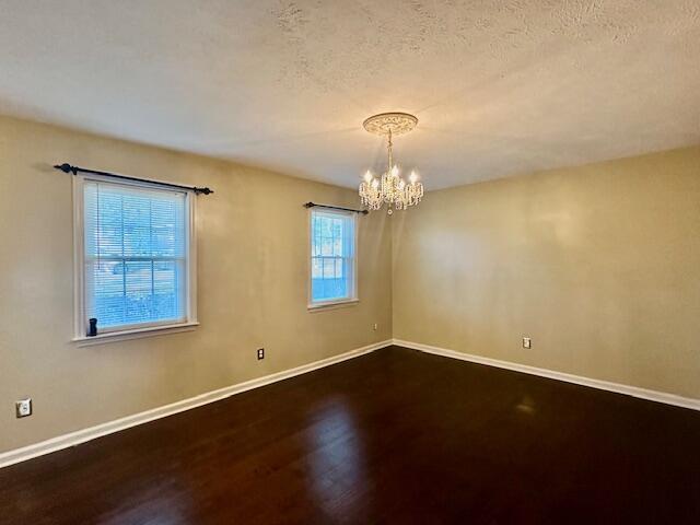 spare room with wood-type flooring, a textured ceiling, and an inviting chandelier