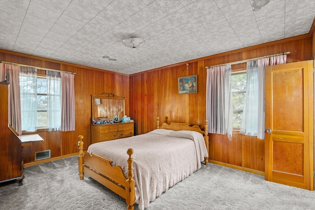 carpeted bedroom featuring wooden walls and multiple windows