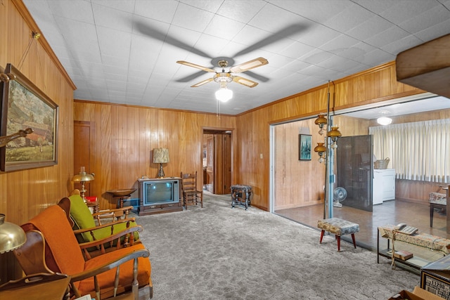 living area with ceiling fan, wooden walls, washer / dryer, and dark colored carpet