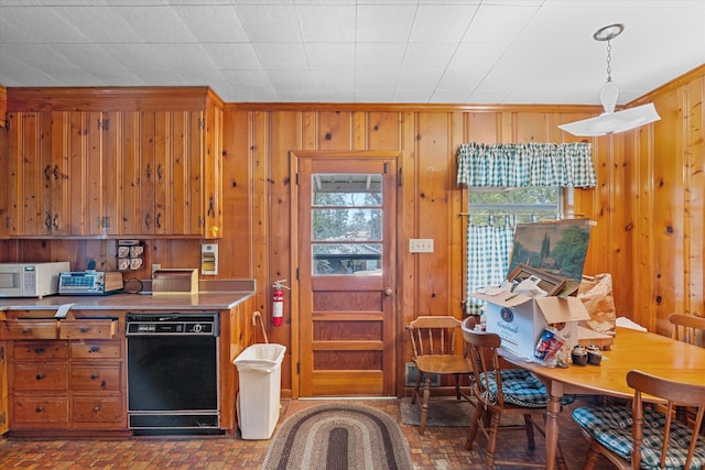 kitchen featuring decorative light fixtures, black dishwasher, and wood walls