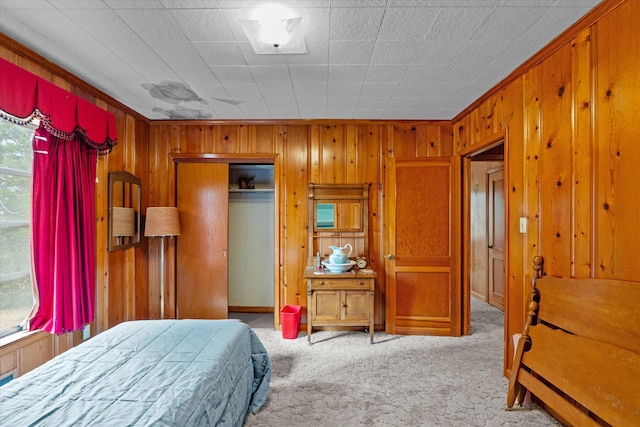 bedroom with crown molding, light colored carpet, wooden walls, and a closet