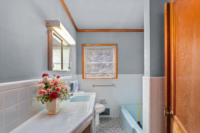 bathroom featuring a bathing tub, tile walls, vanity, toilet, and crown molding