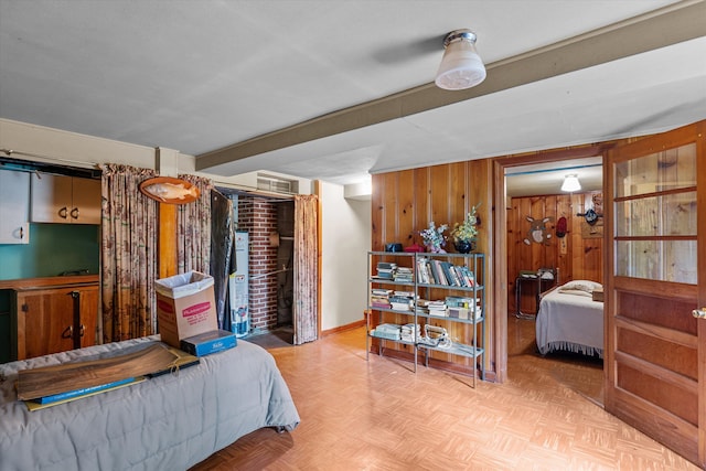 bedroom featuring wooden walls, beamed ceiling, and light parquet floors