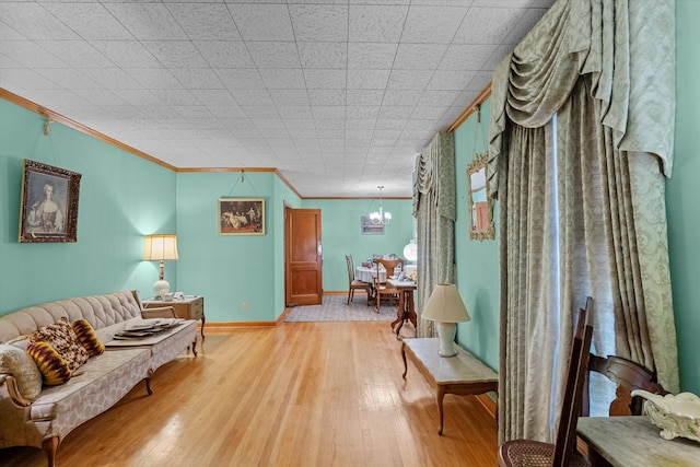 sitting room with crown molding, light hardwood / wood-style flooring, and a chandelier