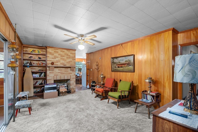 carpeted living room with ceiling fan, a brick fireplace, and wooden walls