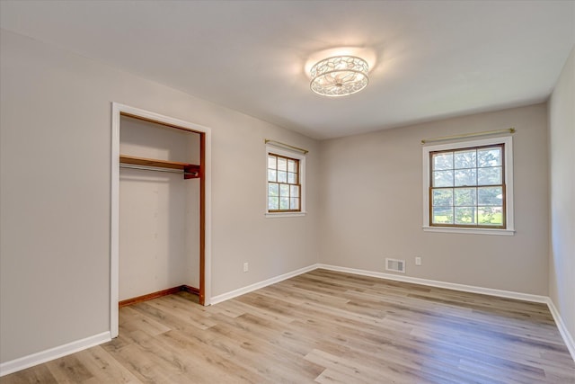 unfurnished bedroom featuring light wood-style flooring, baseboards, and a closet