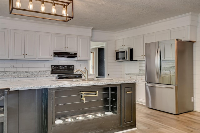 kitchen with appliances with stainless steel finishes, under cabinet range hood, a sink, backsplash, and a textured ceiling