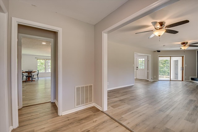 spare room with baseboards, light wood-type flooring, and ceiling fan