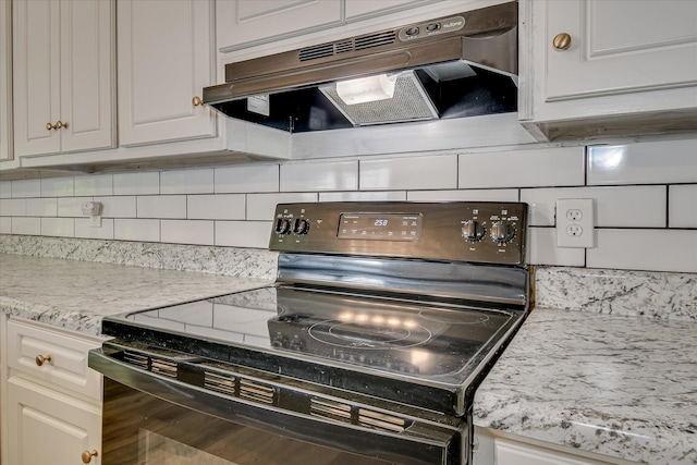 kitchen featuring black range with electric cooktop, under cabinet range hood, backsplash, light countertops, and white cabinets